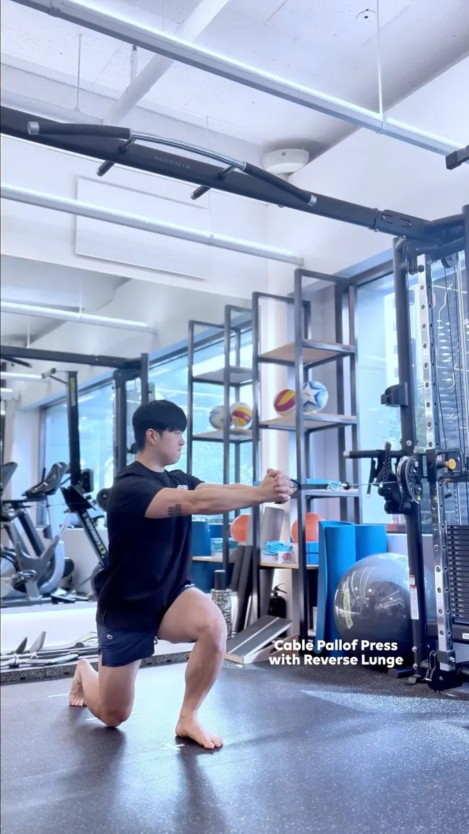 황현우 트레이너 · 케이블 팔로프 프레스와 리버스 런지를 시연하는 모습